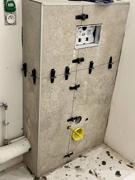 Habillage d'un arrière de WC en faïence et carrelage imitation pierre dans une salle de bain à Ecully près de Lyon